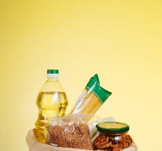 Different Food In Paper Bag on Wooden Table, on Yellow Background. Grocery Shopping Concept.